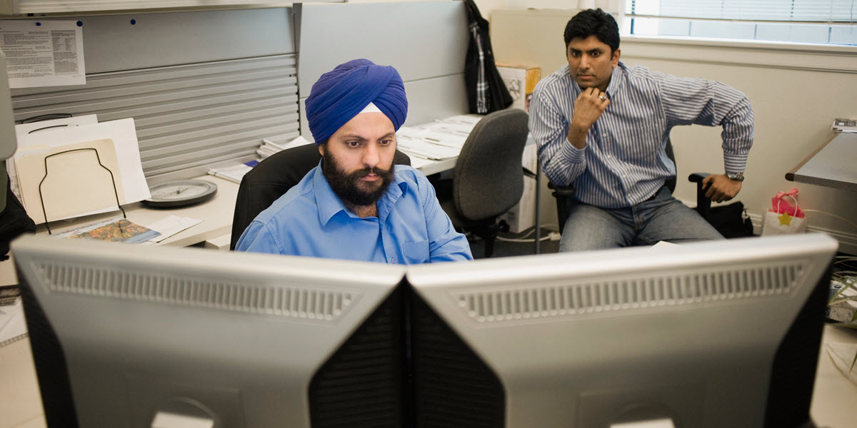 Men working in office looking at computer screen