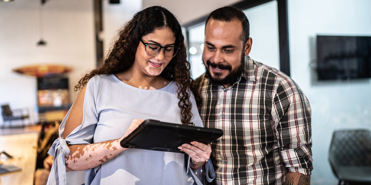 woman and man standing in office looking at tablet