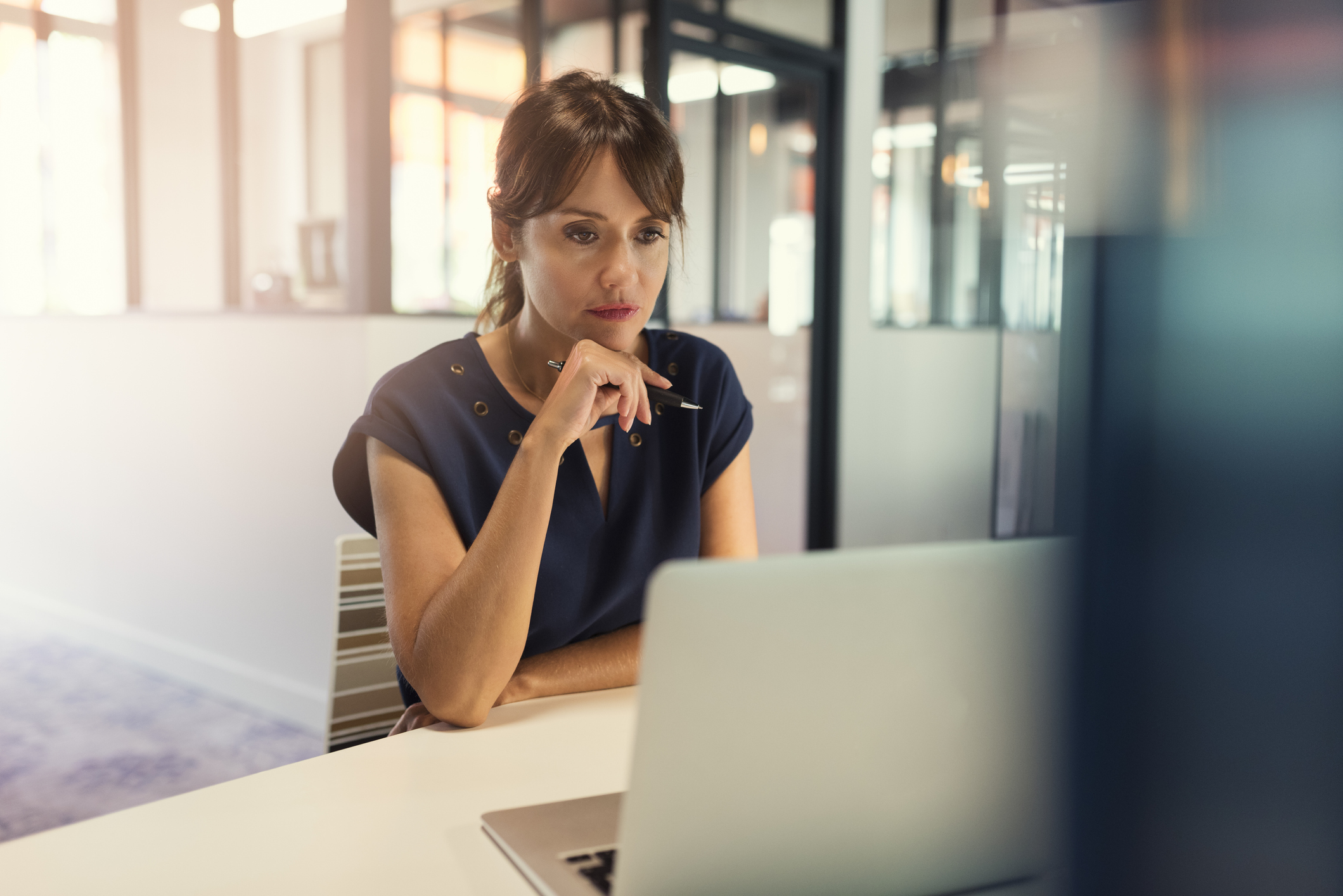 Woman sitting at a desk looking at a computer with a serious face