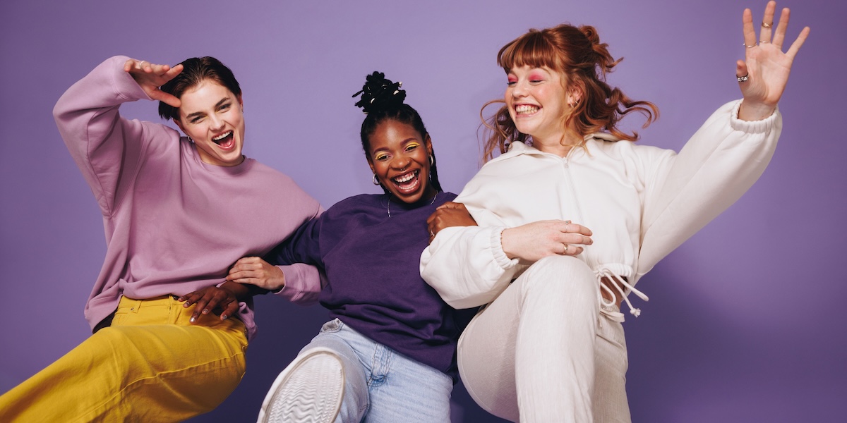Three women linking arms laughing and looking happy