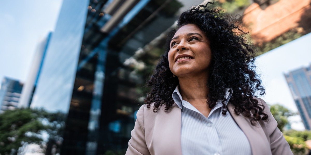professional woman smiling standing outside in front of office building
