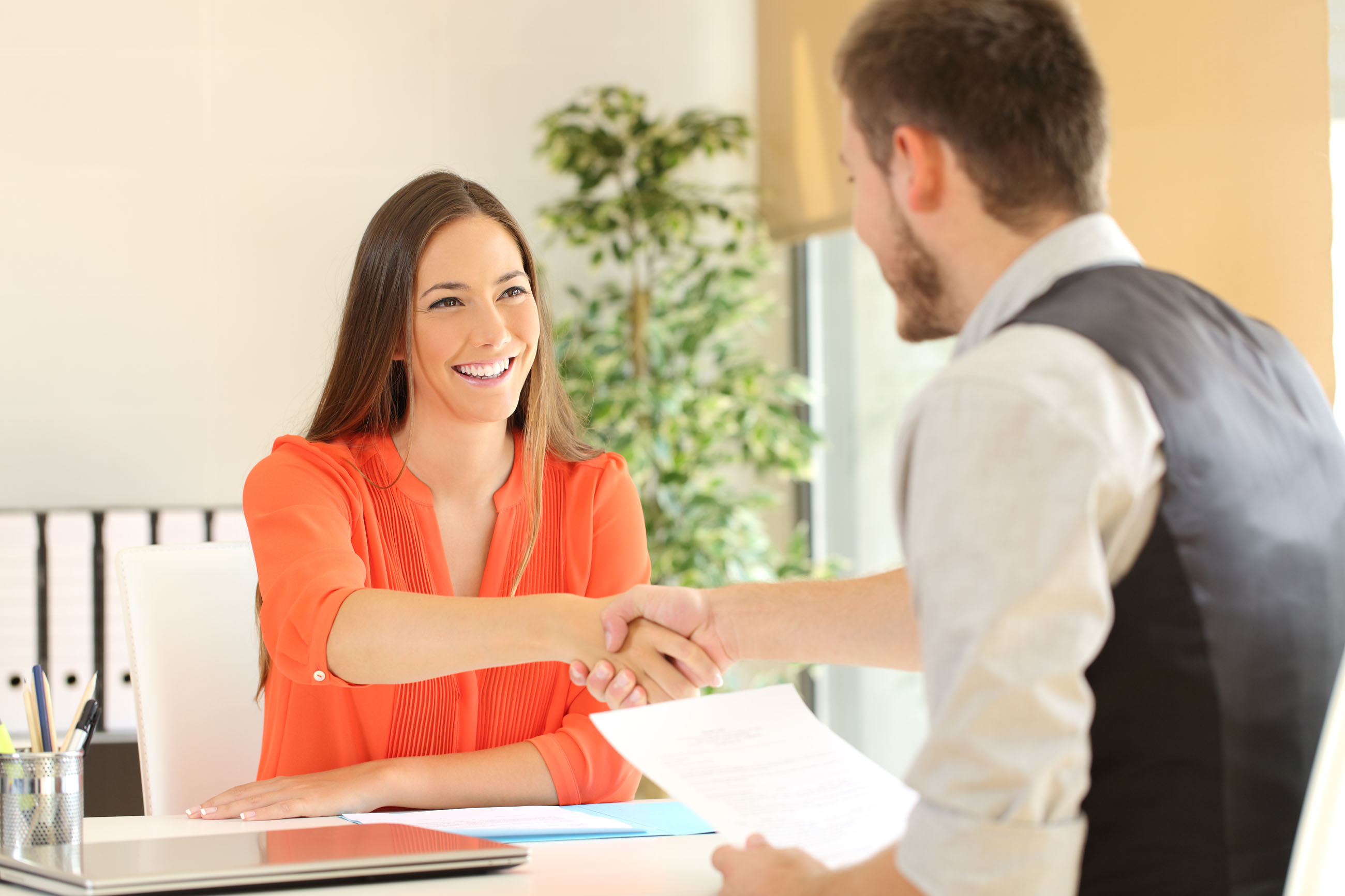 Woman and man shaking hands over a tal