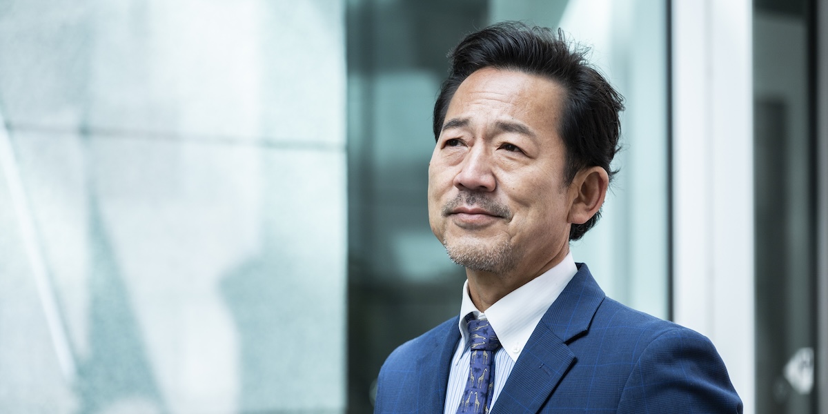 man in suit looking upward with a slight smile