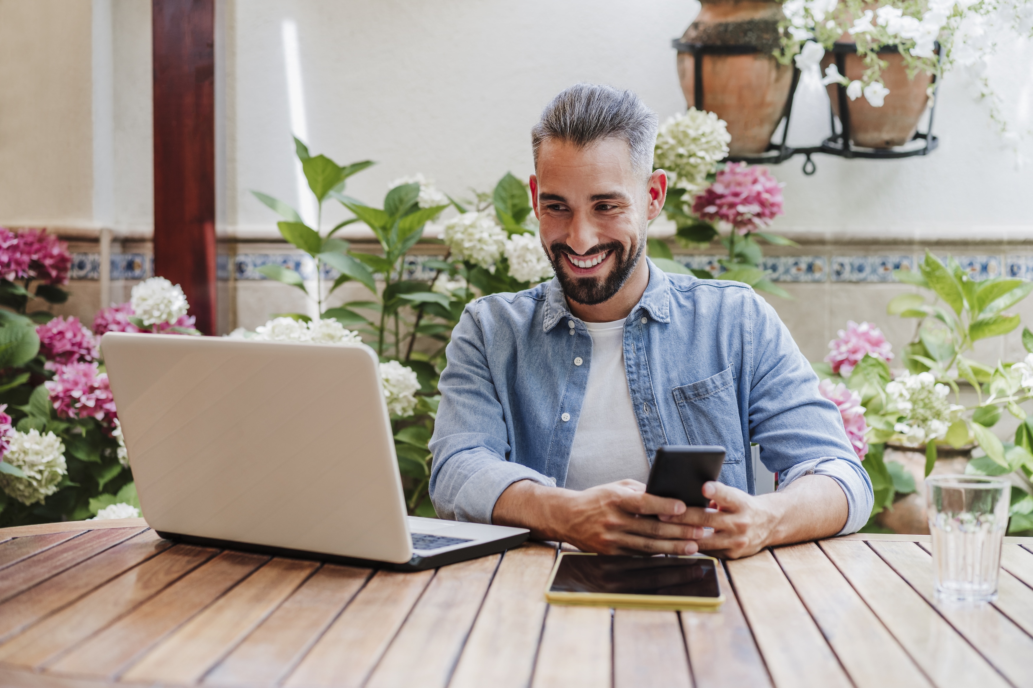 Man on his computer with his phone outside