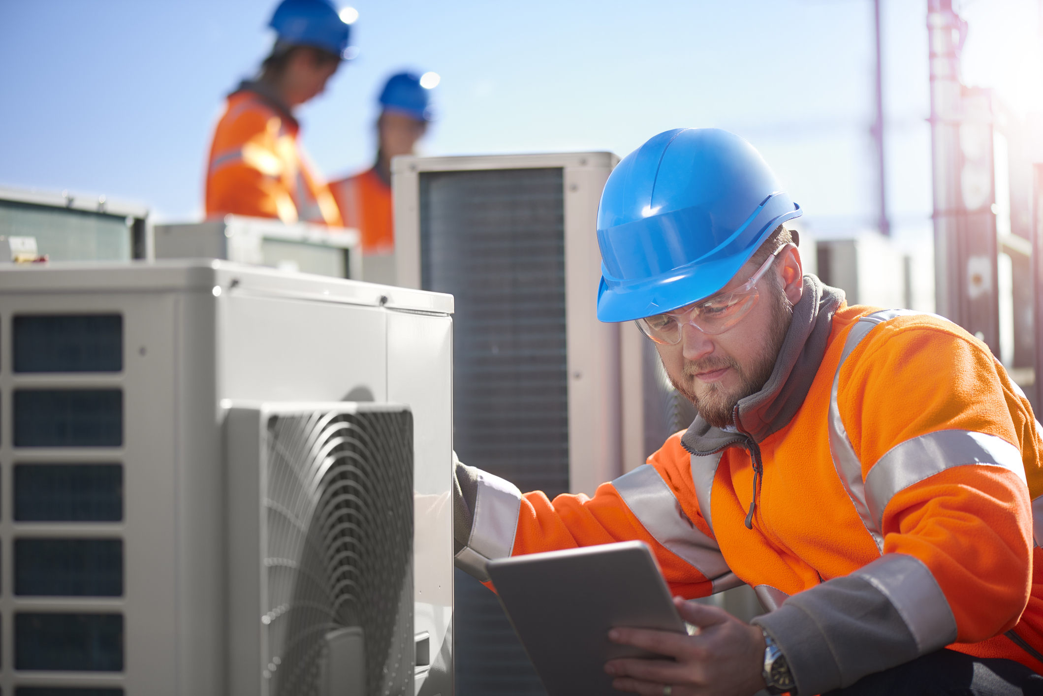 Utilities worker checking a unit looking at a tablet