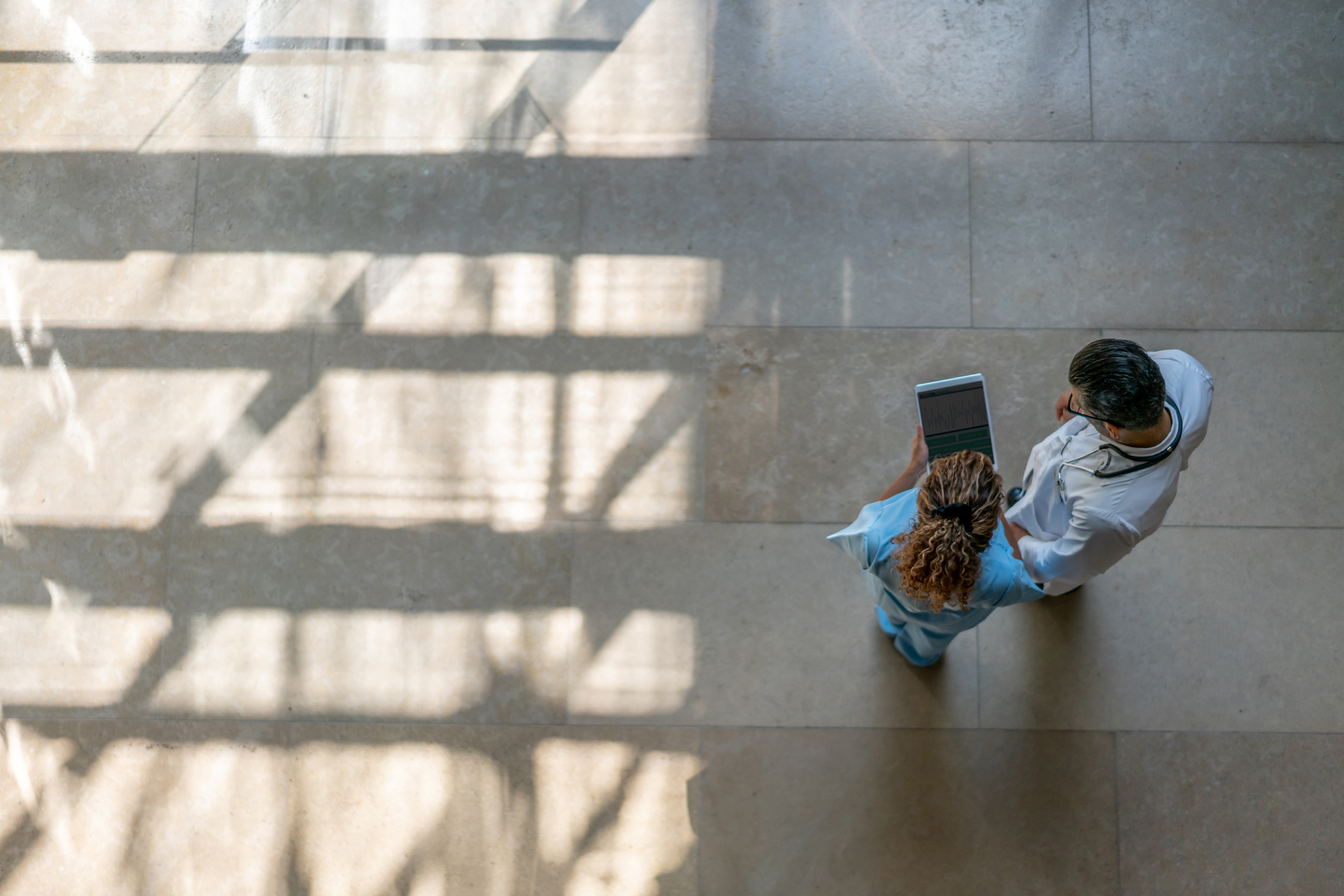 Aerial view of two healthcare professionals looking at a tablet