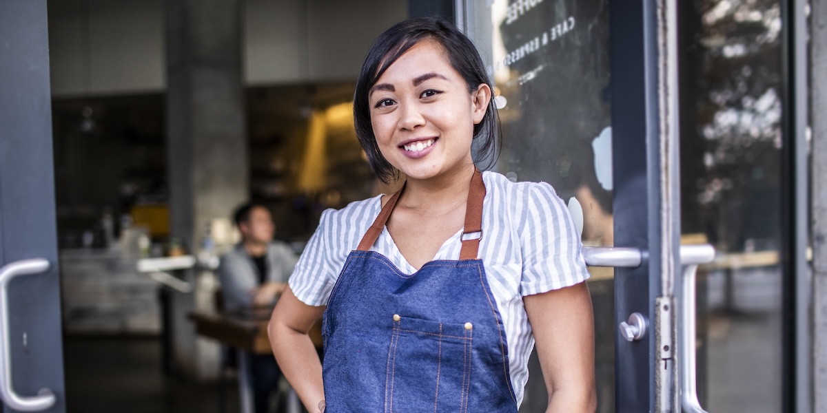 restaurant worker leaning against door smiling