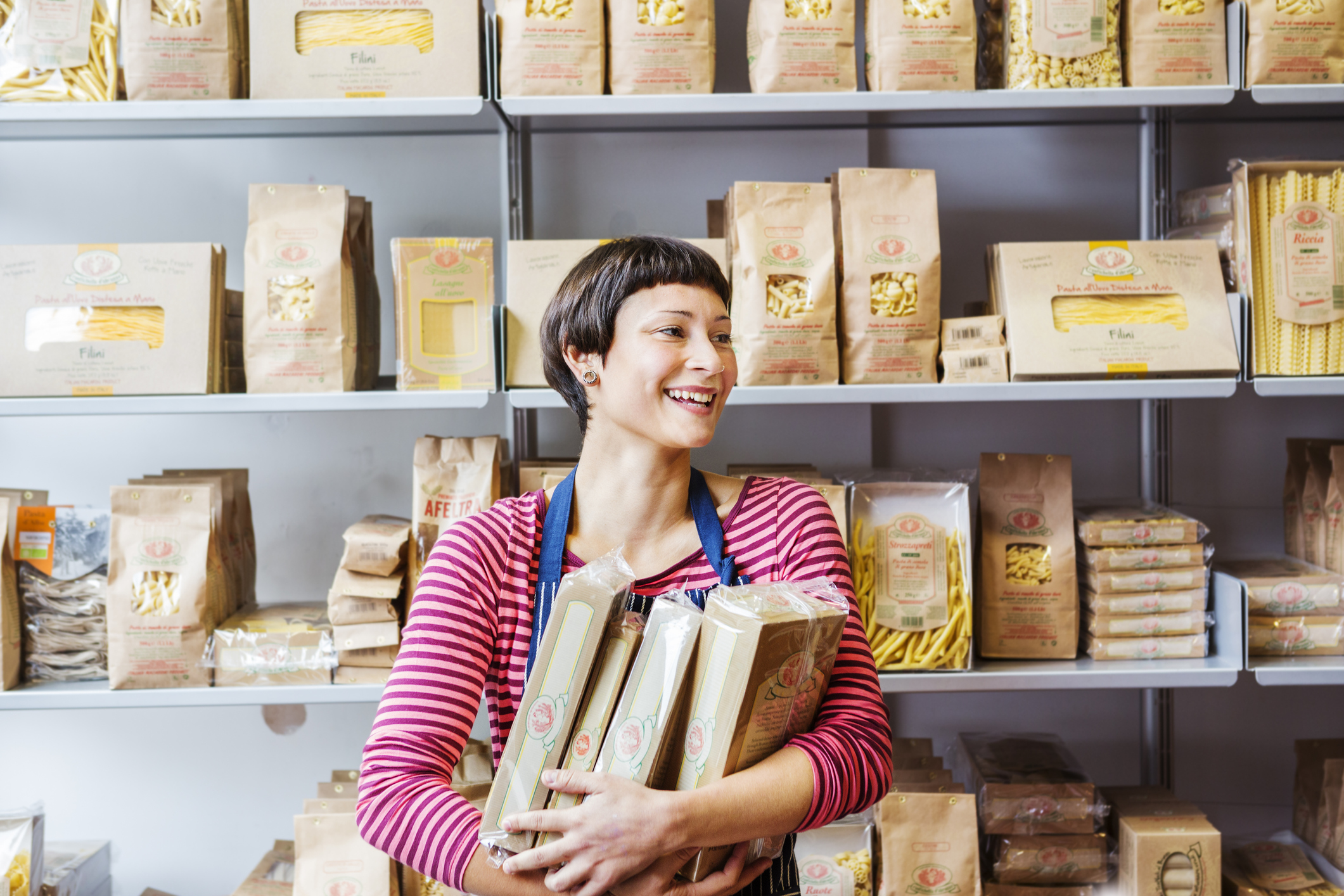 Woman in a store smiling selling packaged pasta