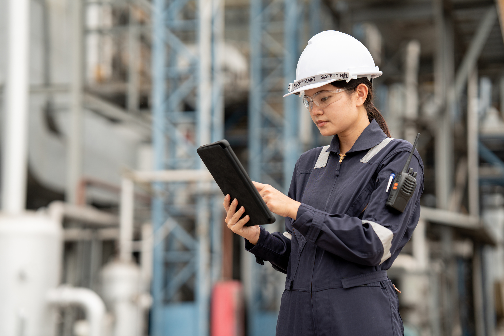 Woman with a hard hat on looking at a tablet in a construction zone