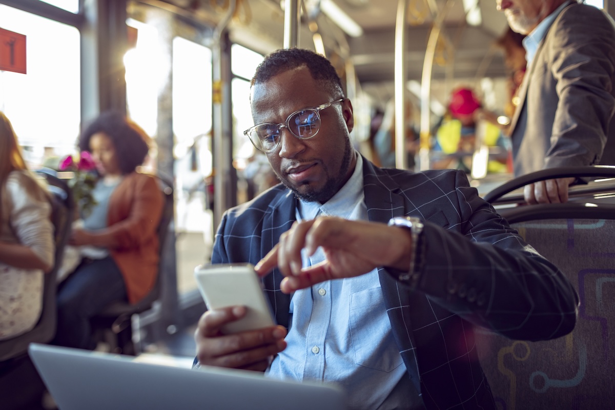 man sitting on bus looking at his travel itinerary
