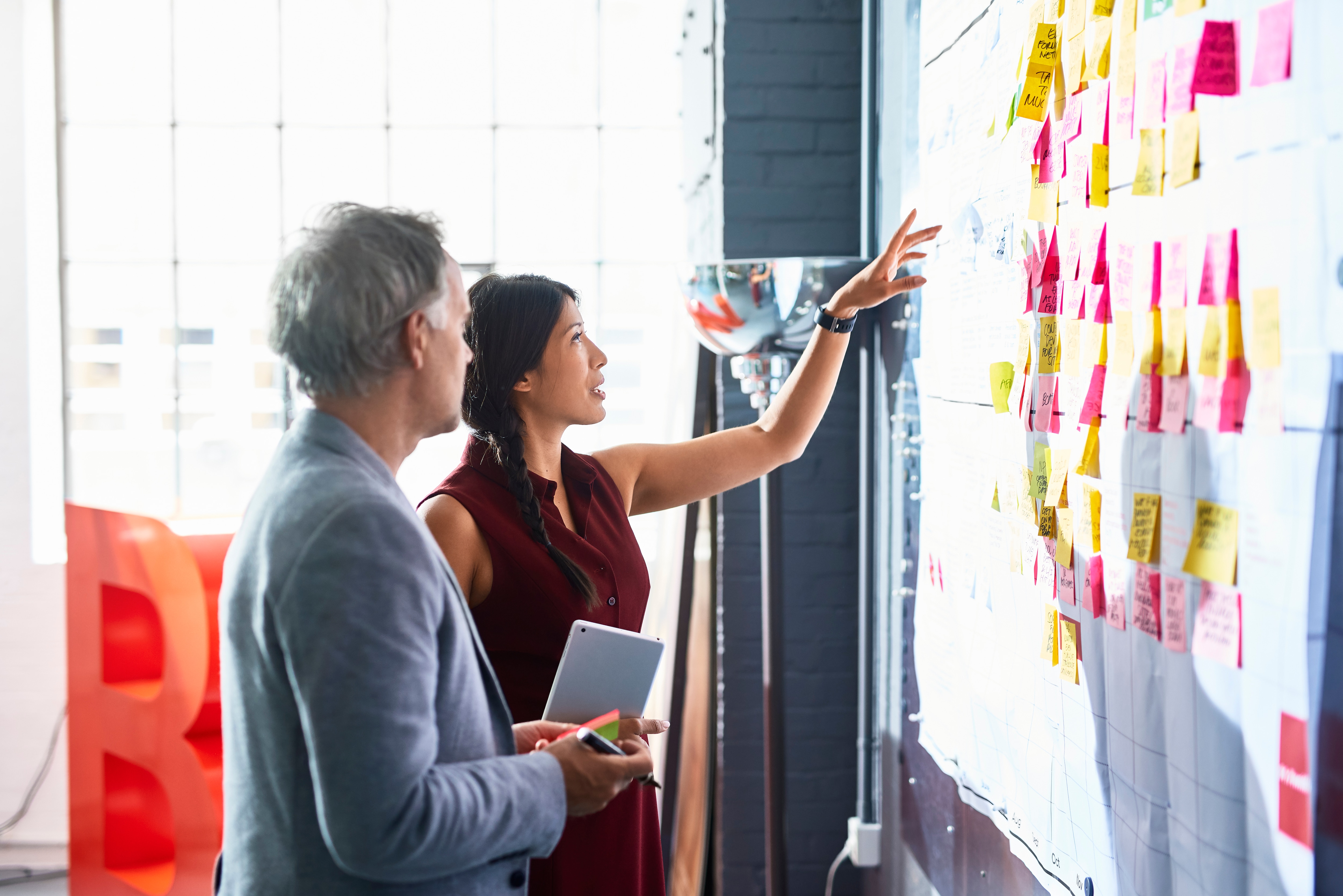 Employees in office looking at whiteboard with sticky notes