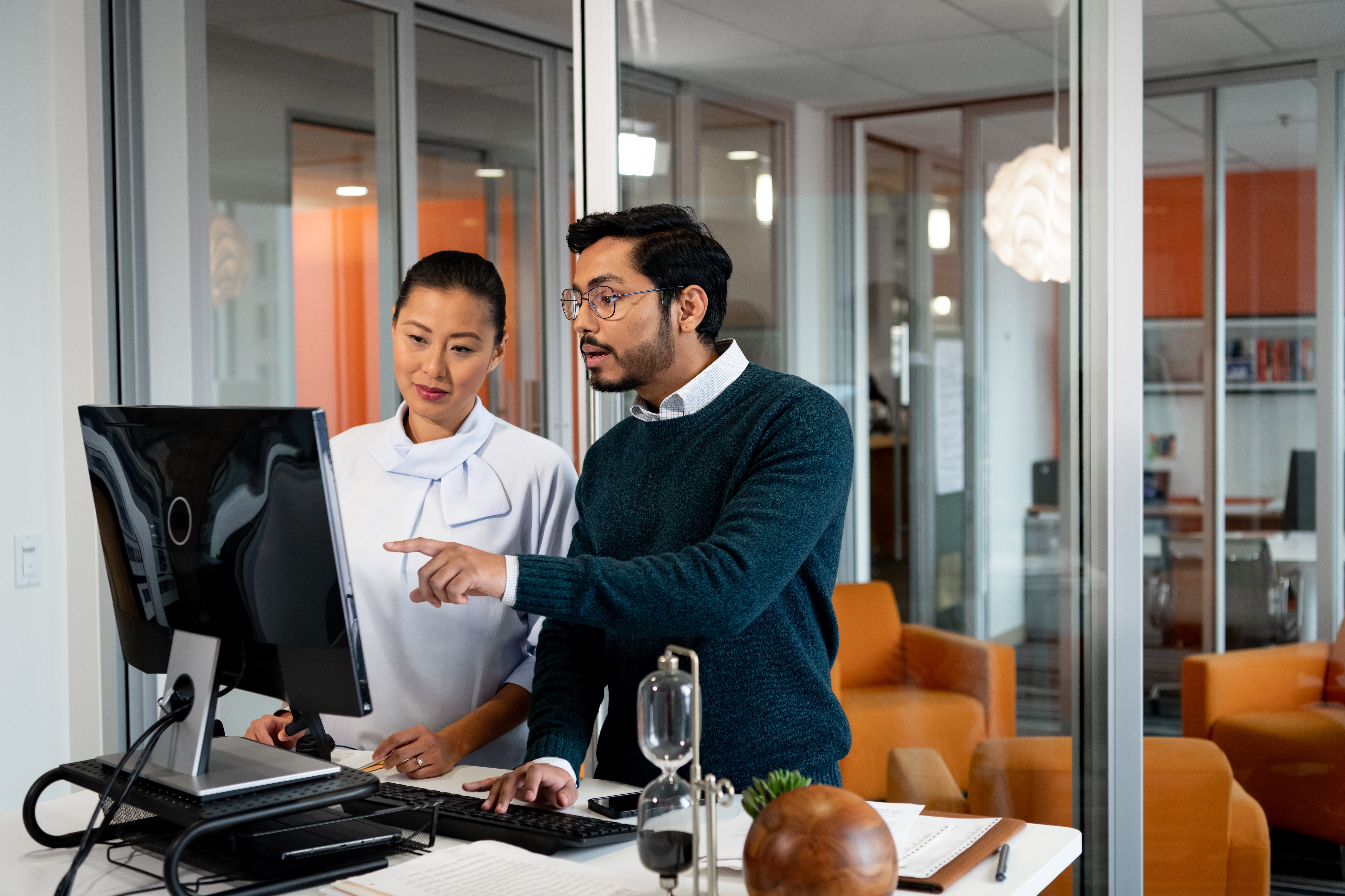 Man and woman look at computer in office