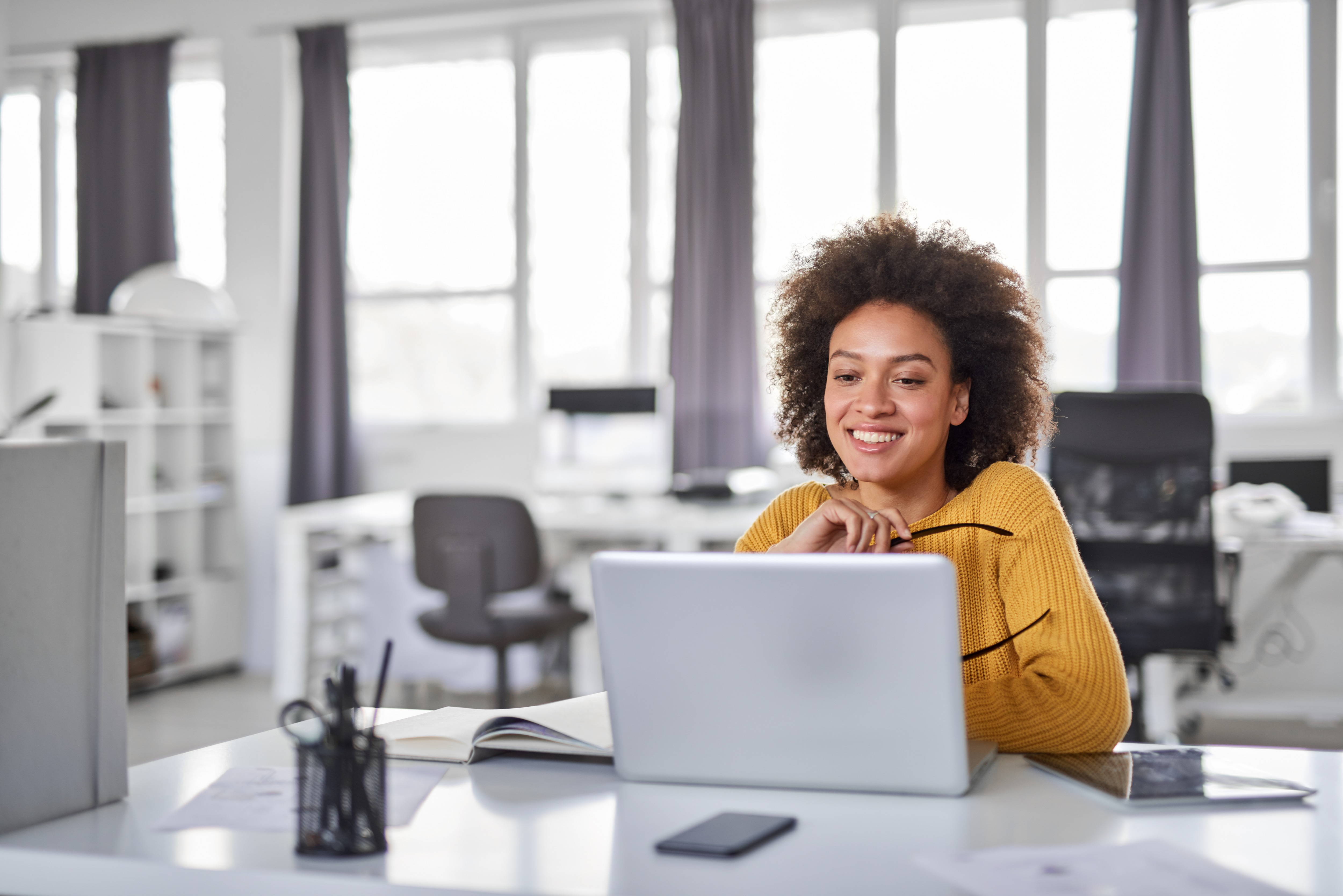 Woman smiling looking at computer sitting at a desk