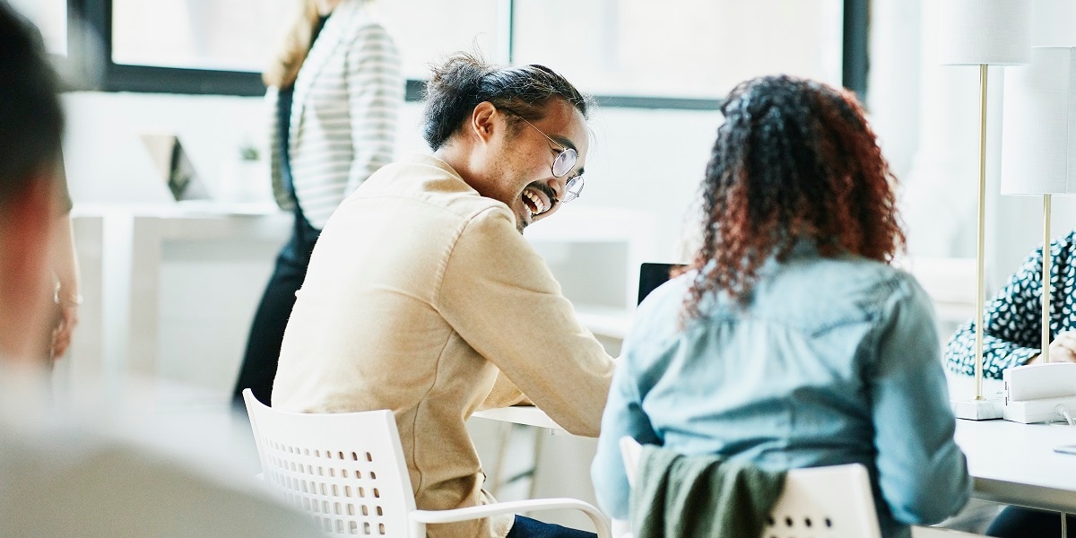 Two co-workers laughing and smiling while working together