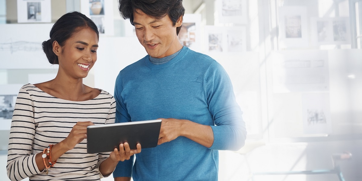 Two business people reviewing information on a tablet in an office setting
