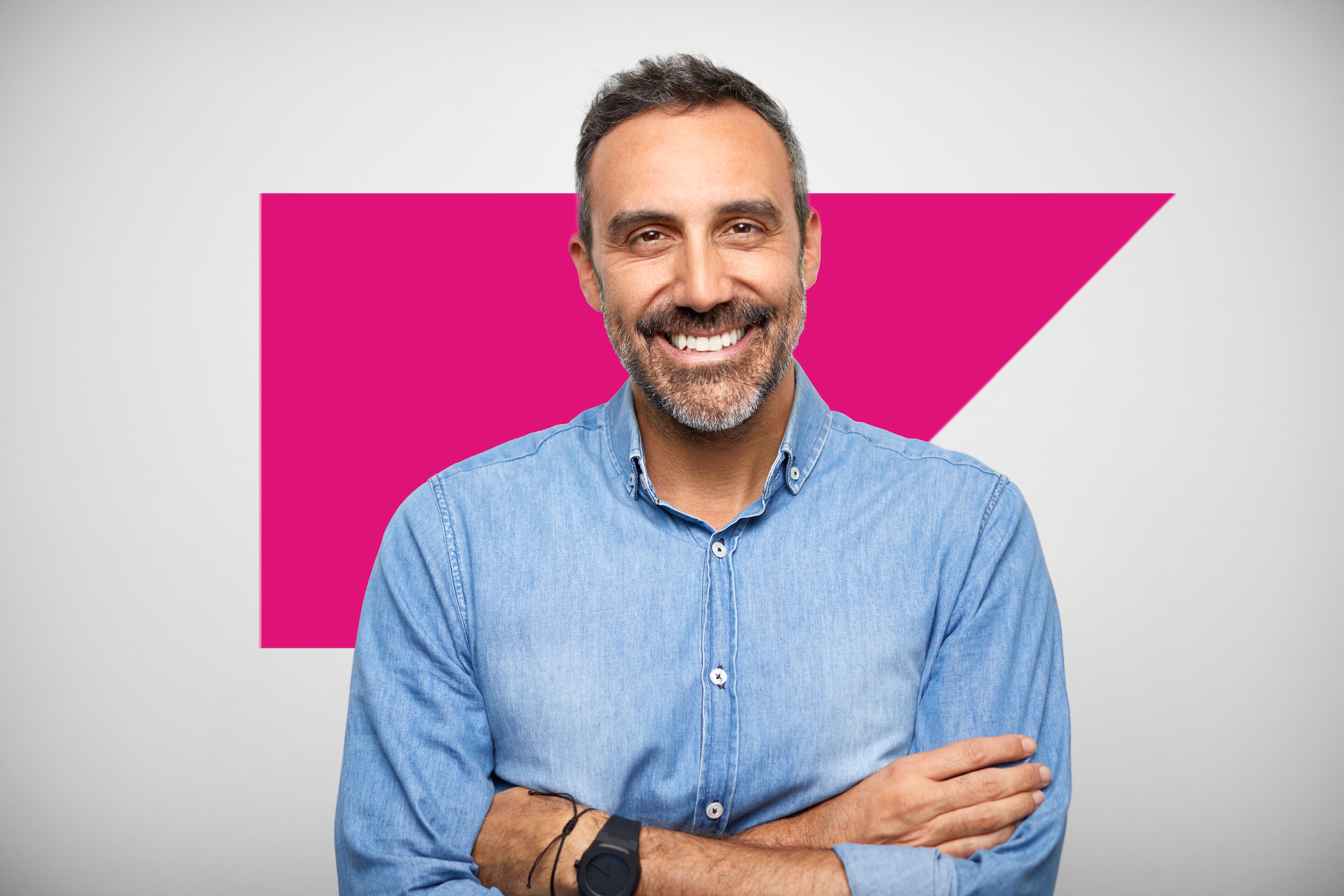 Man in a button down tshirt crossing his arms smiling