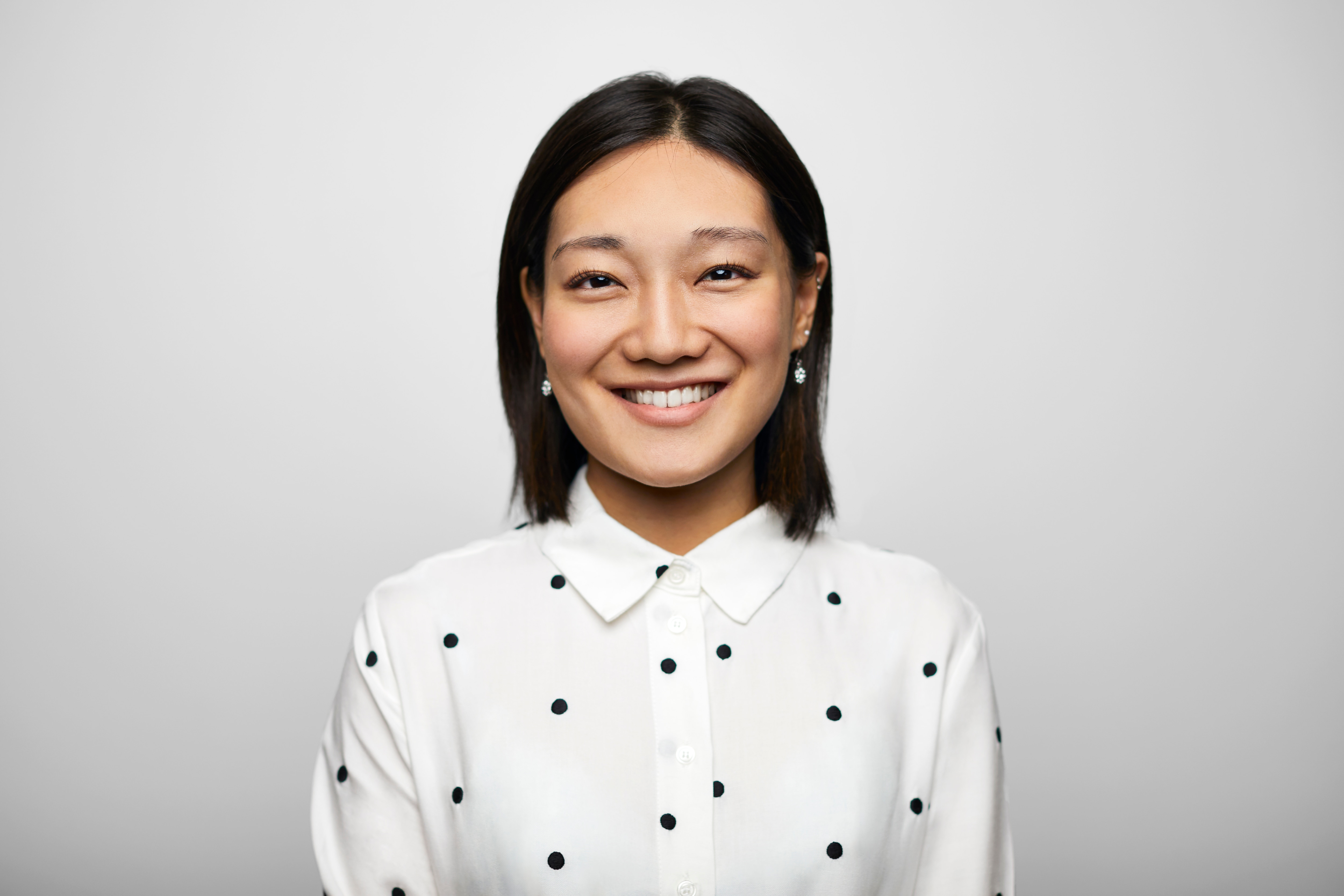 Lady smiling in a polka dot white shirt