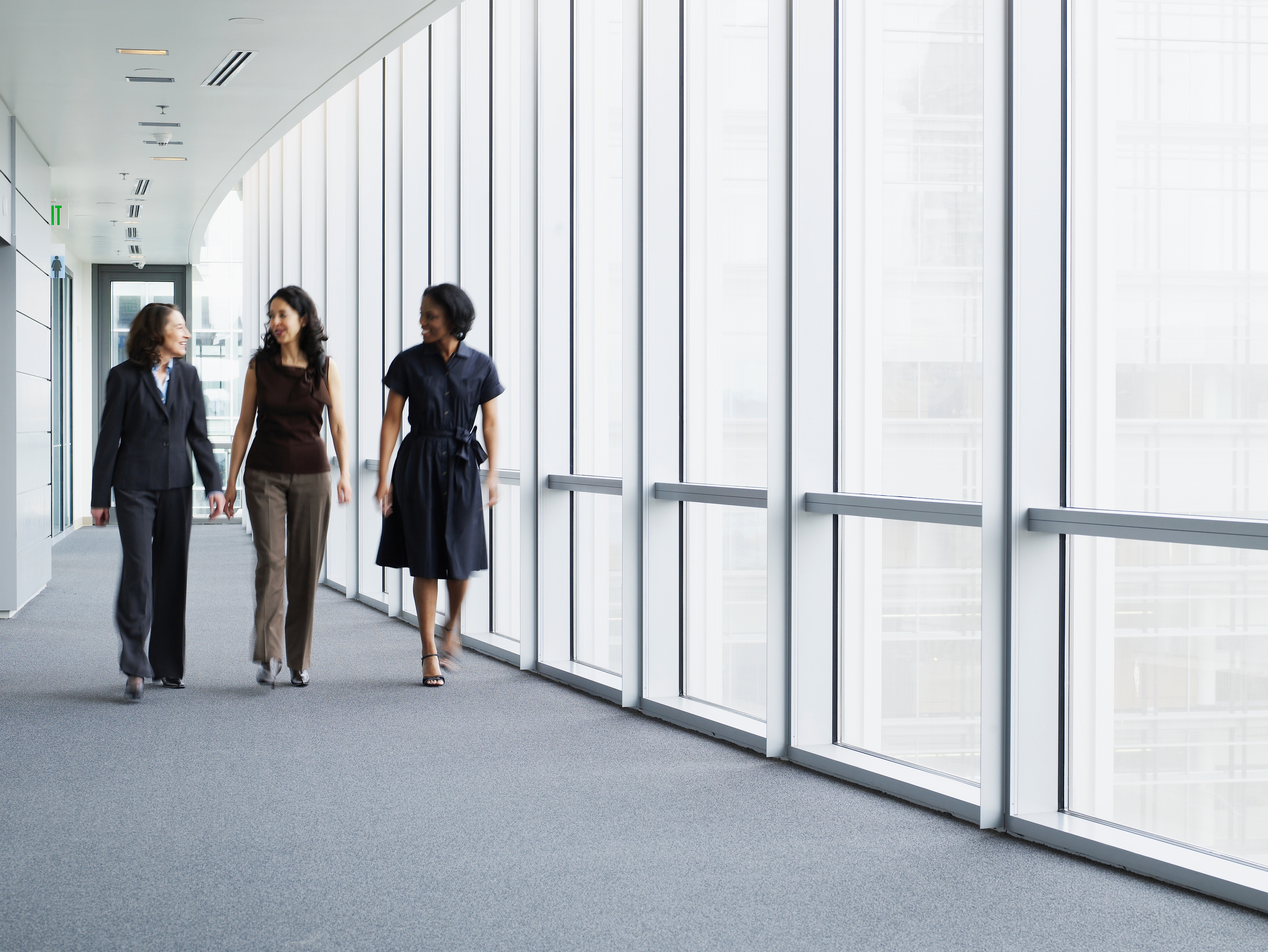 Three women walking down a hall discussing business