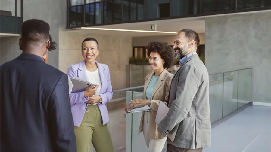 Four business people gathered and laughing indoors