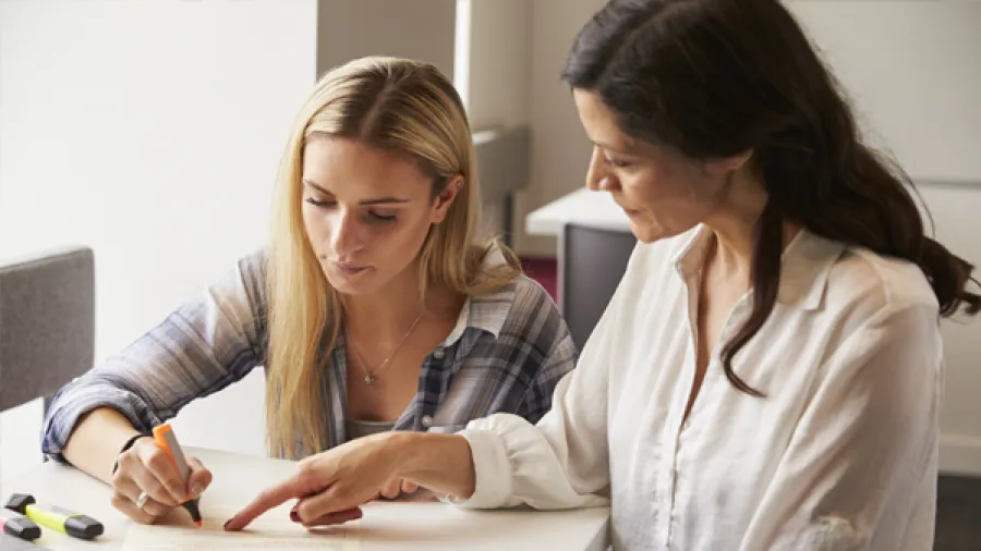 Woman writing in front of another woman