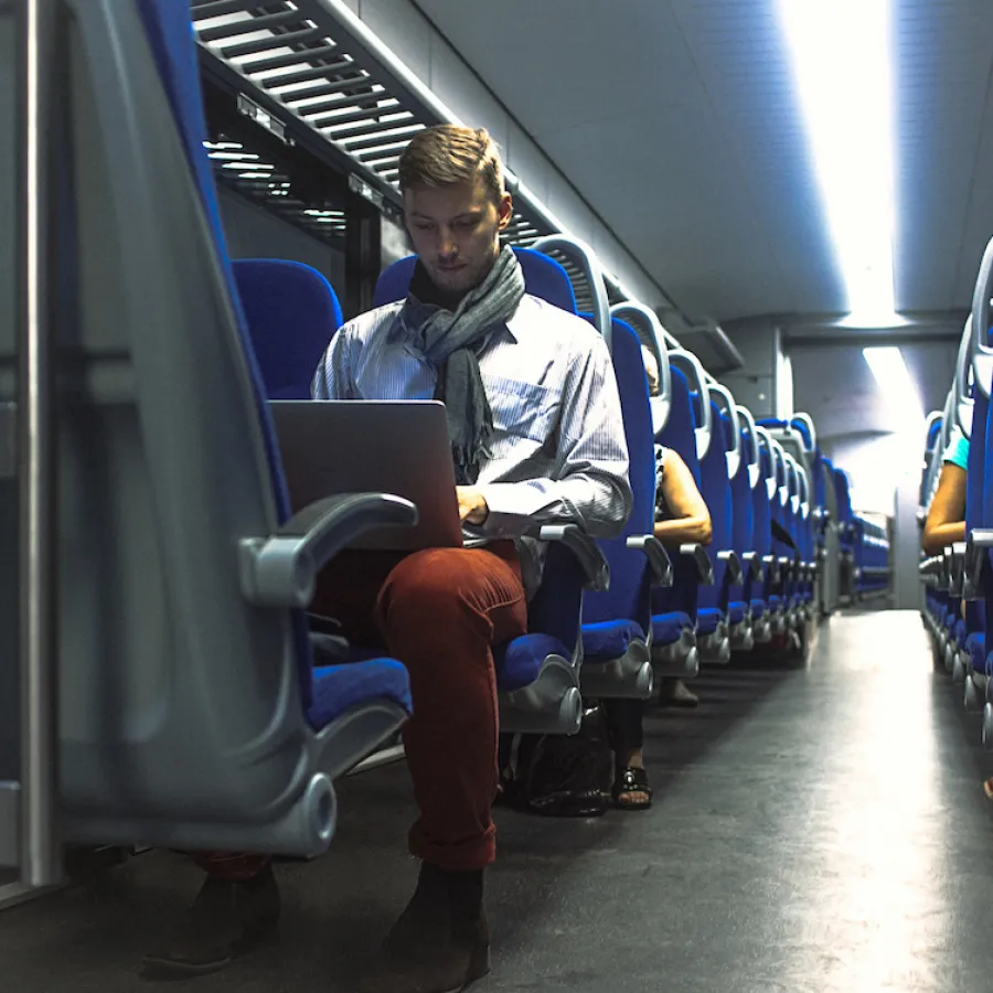 A man works on his laptop while on a train