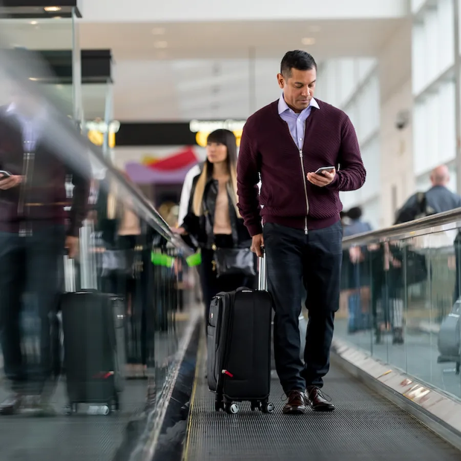 A traveler checks their mobile phone at the airport