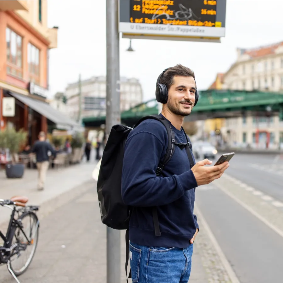 man crossing the road with his phone at bus station