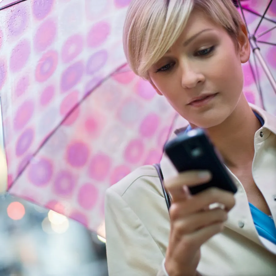 woman holding umbrella looking at phone