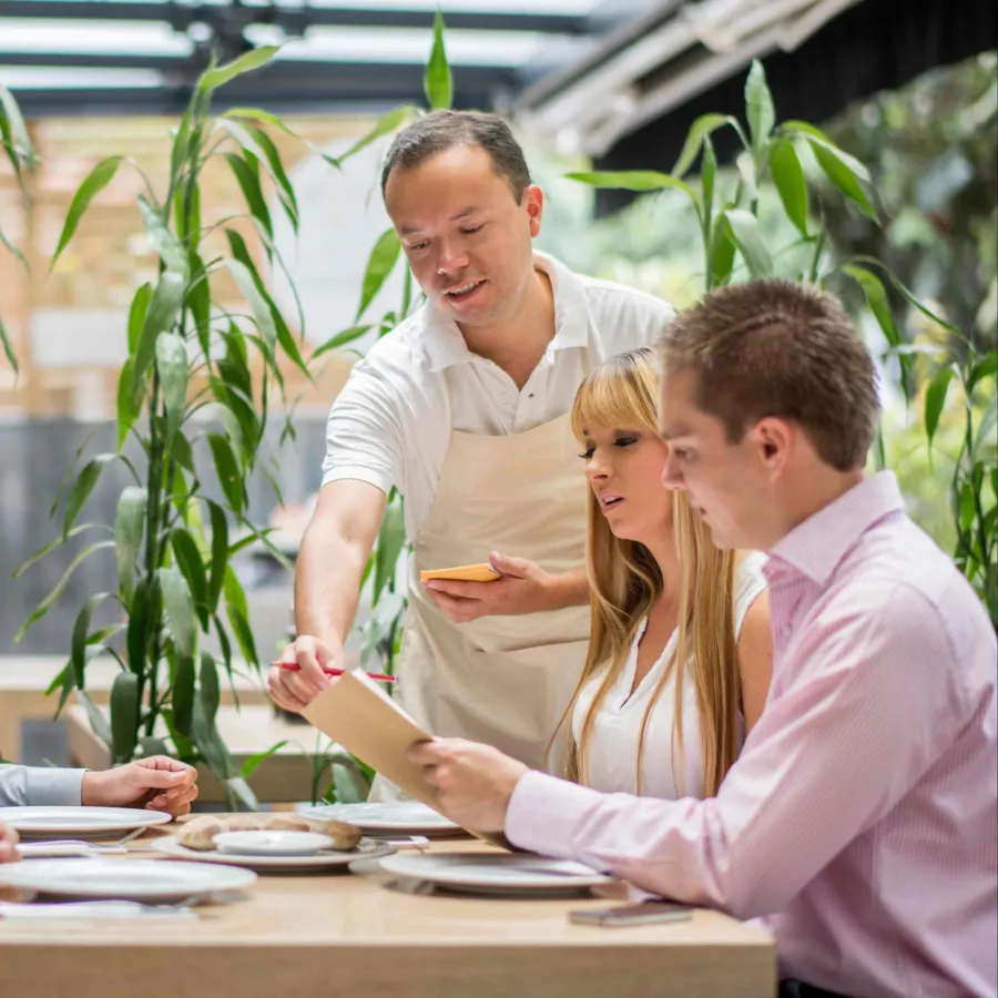 A group of people at a business meal talking to the waiter