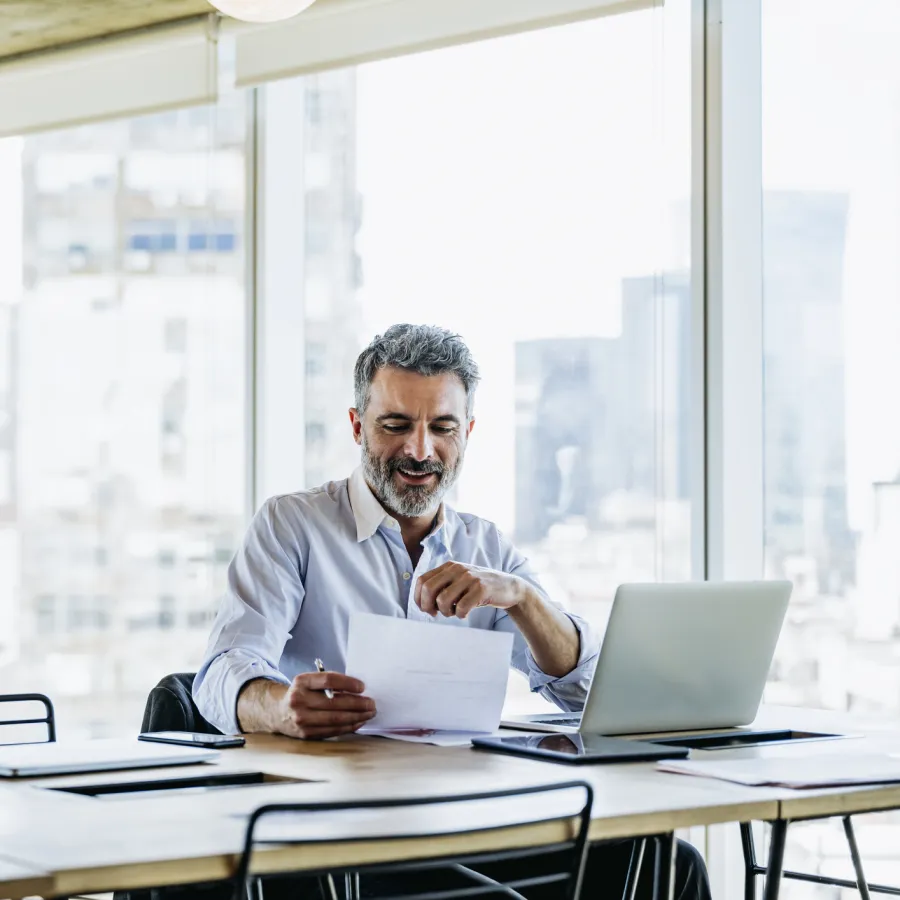 Man looking at a paper on his computer seated at a desk