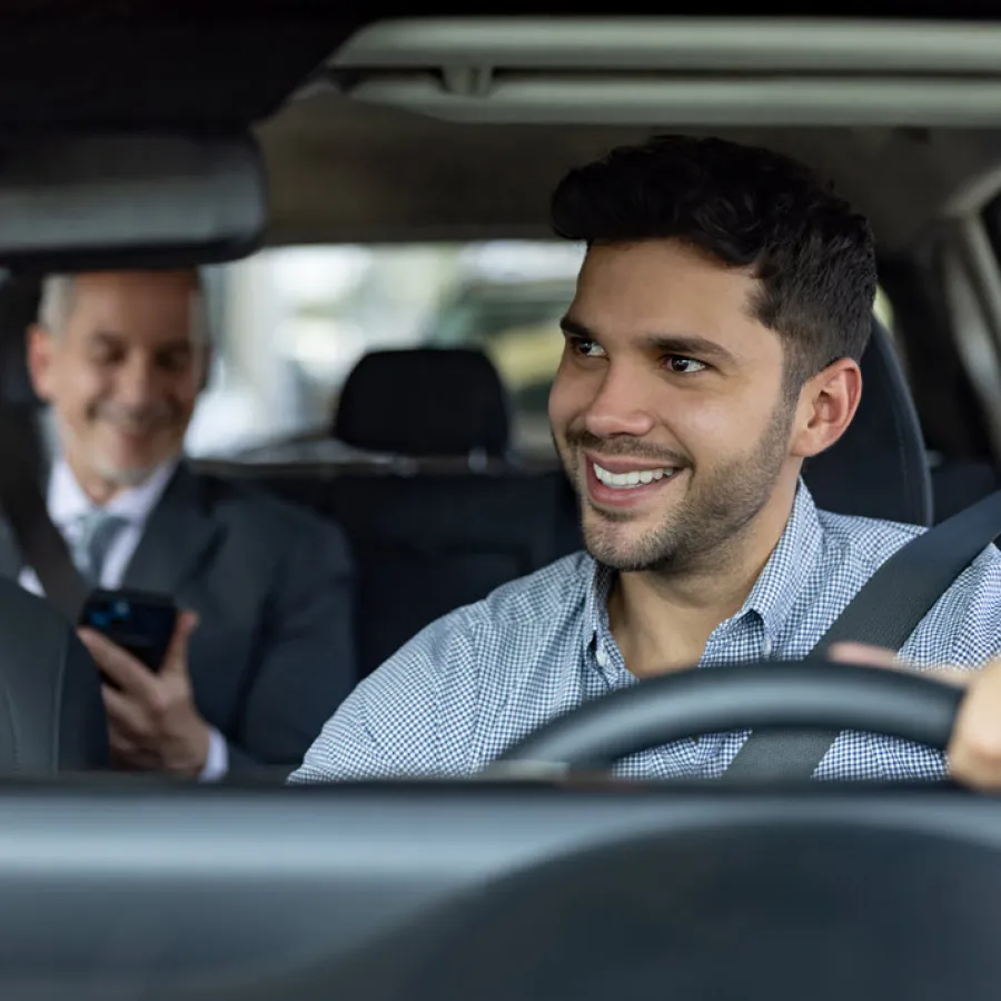 Traveling business man in backseat of rideshare with driver in front seat