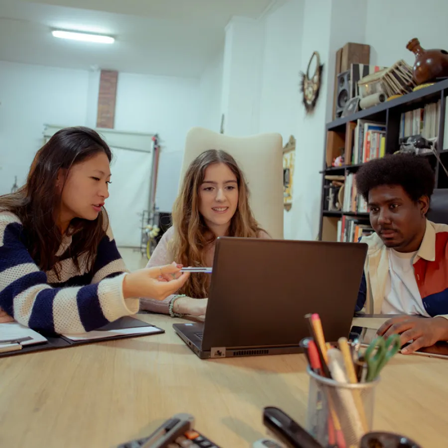 One man and two women working together, looking at laptop