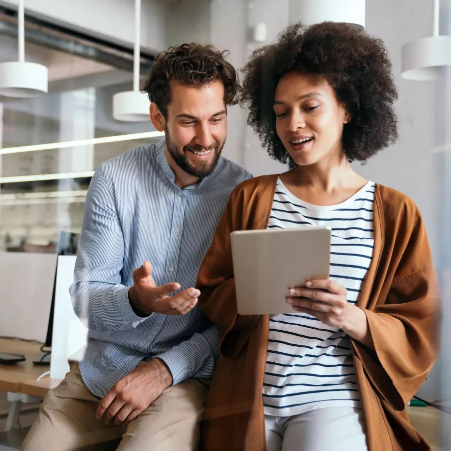 Man and woman in office reviewing a tablet