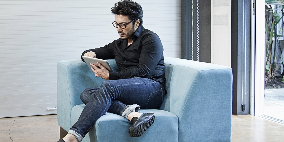 A person sitting on a chair reading a book off a tablet 